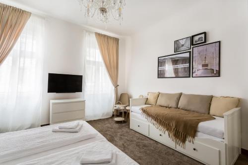 a white bedroom with a bed and a tv at Apartmá Zeyer 1887 in Karlovy Vary