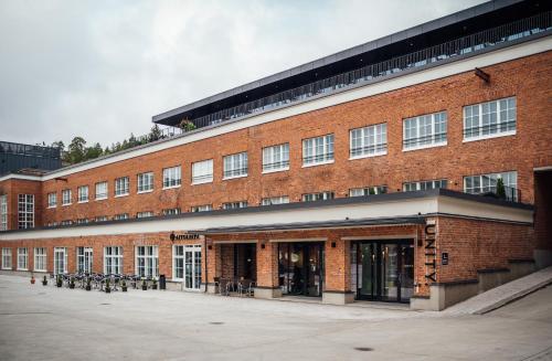 un grand bâtiment en briques rouges avec des tables et des chaises dans l'établissement UNITY Tampere Trikootehdas, à Tampere