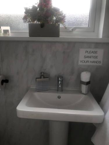 a bathroom sink with a sign that reads please estimate your tanks at Alderberry Lodge in Newquay