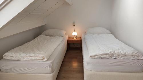 two beds in a room with a table with a lamp at Appartement met 3 slaapkamers vlakbij strand en centrum in Zoutelande