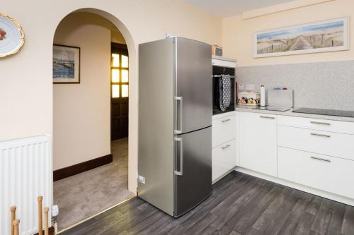 a stainless steel refrigerator in a kitchen with white cabinets at No27 Willowbank in Dunkeld