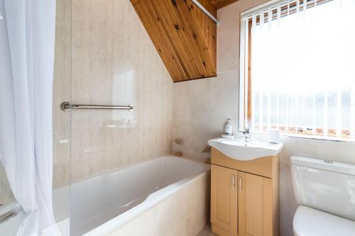een badkamer met een wit bad en een wastafel bij No27 Willowbank in Dunkeld