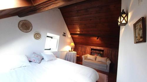 Schlafzimmer mit einem weißen Bett und Holzwänden in der Unterkunft Casa do Patio - Très charmante villa 12 personnes 5ch avec piscine in São Bartolomeu