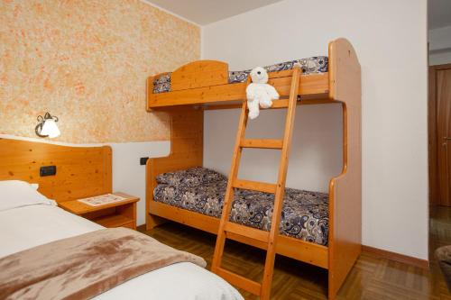 a bedroom with bunk beds with a teddy bear on a ladder at Hotel Biancospino in Lanzada