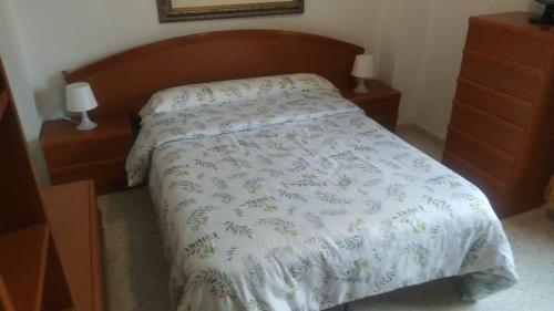 APARTAMENTO LUMINOSO EN URBANIZACIÓN PRIVADA في غرناطة: غرفة نوم مع سرير مع لحاف أبيض وجلستين ليلية