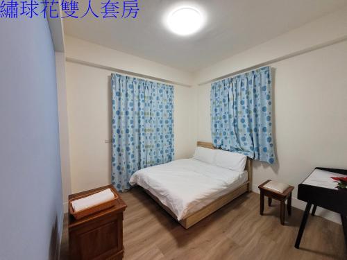 um pequeno quarto com uma cama e cortinas azuis em Flower B&B em Hualien