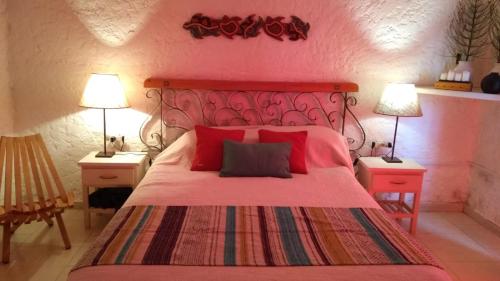 1 dormitorio con 1 cama roja, 2 mesas y 2 lámparas en CASA OCTUBRE, en Aguas Dulces