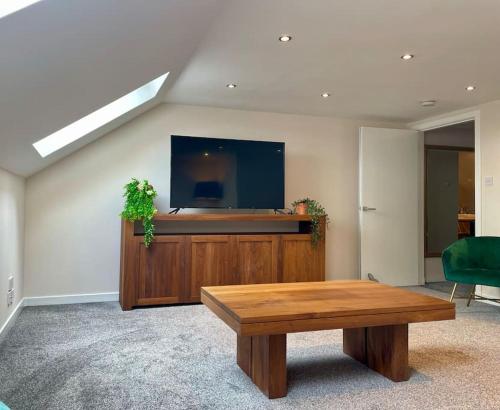 un soggiorno con tavolo e TV a schermo piatto di Vennel Street Apartments a Stewarton
