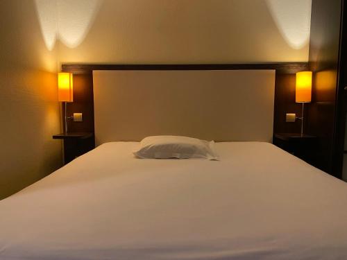 a bed with a white pillow on it in a room at Hotel Inn Design Le Havre in Montivilliers