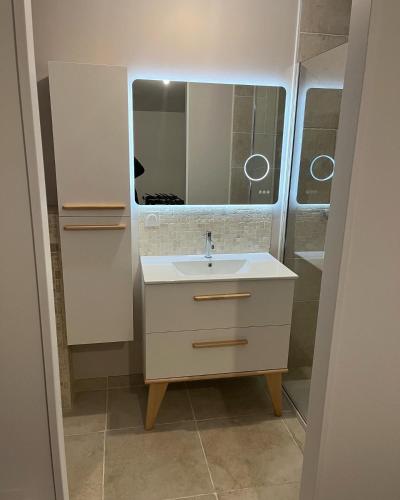 une salle de bain avec un lavabo et un miroir dans l'établissement Côté Jardin, à Bobital