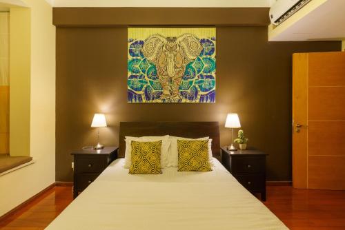 a bedroom with a large bed with two lamps and a painting at Carlsen Residence in Colombo