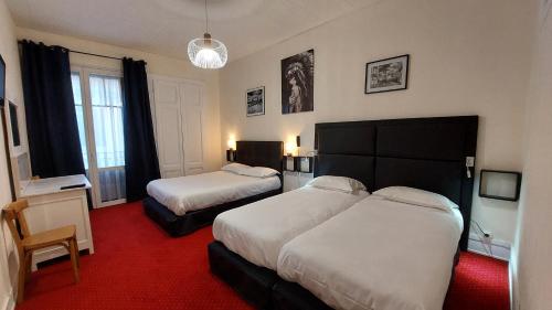a hotel room with two beds and a red carpet at Hôtel du Palais in Évian-les-Bains