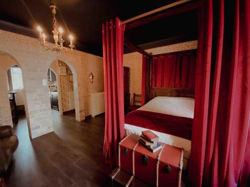 ein Schlafzimmer mit einem Bett mit roten Vorhängen und einem Koffer in der Unterkunft LA SALLE DES SORTILÈGES in Perpignan