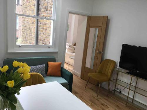 a living room with a table and a television at Newly refurbished 2-bedroom flat in Notting Hill in London