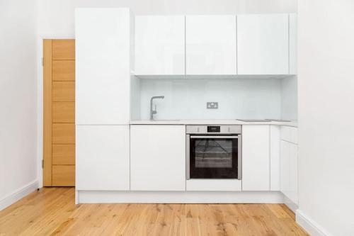 uma cozinha branca com armários brancos e um lavatório em Newly refurbished 2-bedroom flat in Notting Hill em Londres