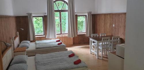 Penzion a restaurace U báby Šubrový في Kokořín: غرفة بثلاث اسرة وطاولة ونوافذ