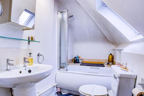 a white bathroom with a sink and a toilet at Entire Artistic Open-Plan Top Floor Apartment in Westcliff-On-Sea