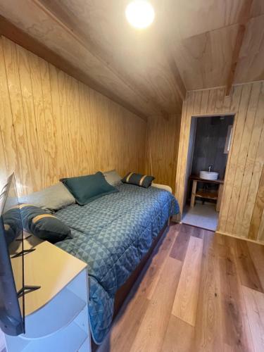 a bedroom with a bed in a room with wooden walls at Tiny house los zorzales in Castro