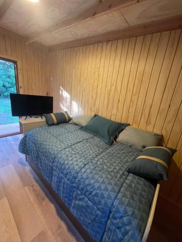 sypialnia z łóżkiem w drewnianej ścianie w obiekcie Tiny house los zorzales w mieście Castro
