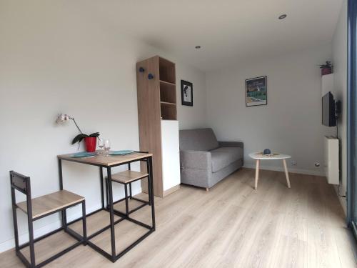 a living room with a couch and a table and a chair at La cabane au fond du jardin - 300m de la plage in Saint Malo