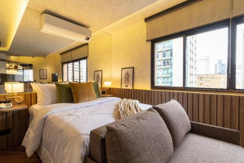1 dormitorio con 1 cama grande y 1 sofá en Vossa Bossa Flat Jardins, en São Paulo