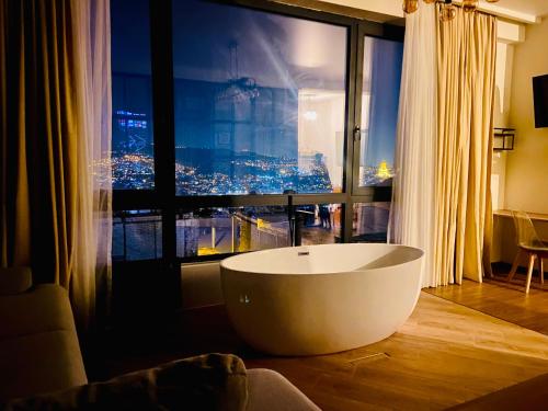 a bath tub in a room with a large window at LUXURY APARTMENT IN OLD TBILISI WITH TERRACe in Tbilisi City