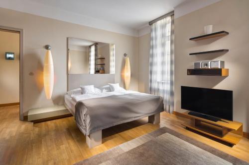 een slaapkamer met een bed en een flatscreen-tv bij Mamaison Residence Belgická Prague in Praag
