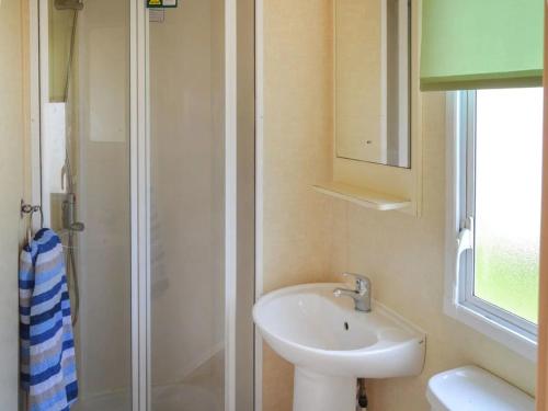 a small bathroom with a sink and a shower at Norfolk Lavender Caravan - Sleeps 4 - WiFi and Sky TV Included in Bacton