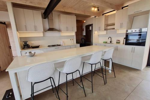 una cucina con un grande bancone bianco e sedie di Casa Blanca Fundo Duao a Iloca
