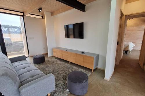 een woonkamer met een bank en een flatscreen-tv bij Casa Blanca Fundo Duao in Iloca