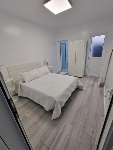 a white bedroom with a bed and two windows at GUANARTEME 33 in Las Palmas de Gran Canaria