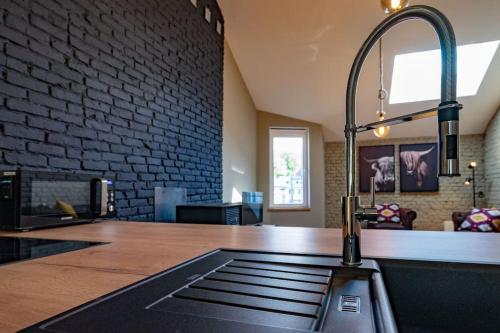 a kitchen with a sink and a brick wall at Le Comble Amoureux in La Roche-en-Ardenne