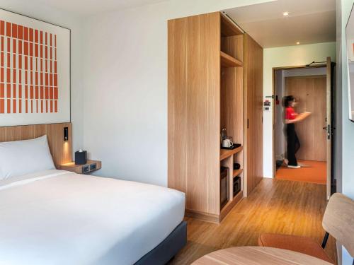 1 dormitorio con 1 cama y 1 mujer en el pasillo en ibis Chiang Mai Nimman Journeyhub en Chiang Mai