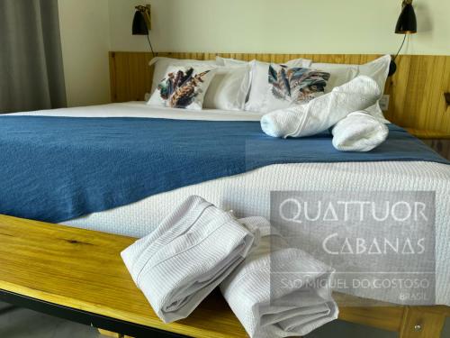 - un lit avec des serviettes blanches et un panneau sur celui-ci dans l'établissement QUATTUOR Cabanas, à São Miguel do Gostoso