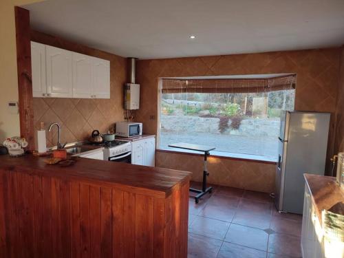 een keuken met een wastafel, een koelkast en een raam bij Casa Mamalluca in Vicuña