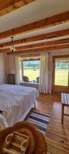 1 dormitorio con cama grande y ventana grande en La Pilarica Lodge en Cholila