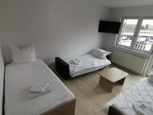 a room with two beds and a bench and a window at Ferdimesse Apartments 2 in Cologne
