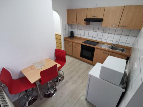 a small kitchen with a wooden table and red chairs at Ferdimesse Apartments 2 in Cologne