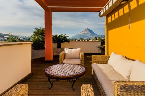 a patio with a couch and a table and a mountain at Albamar Duplex Apartment Javea Arenal by Rock Rentals in Jávea
