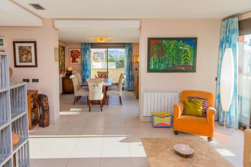 a living room with an orange chair and a table at Albamar Duplex Apartment Javea Arenal by Rock Rentals in Jávea
