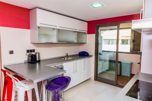 a kitchen with white cabinets and purple stools at Albamar Duplex Apartment Javea Arenal by Rock Rentals in Jávea