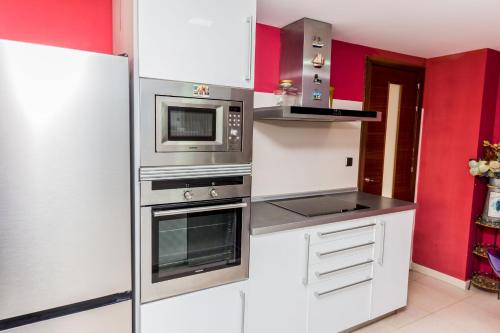 a kitchen with stainless steel appliances and red walls at Albamar Duplex Apartment Javea Arenal by Rock Rentals in Jávea