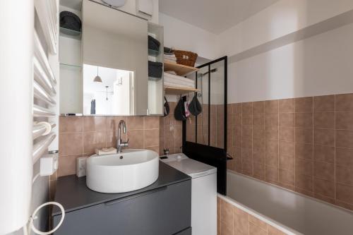 a bathroom with a white sink and a tub at Appartement très calme, terrasse & jardin en ville in Besançon