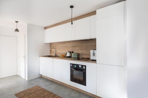 Biała kuchnia z białymi szafkami i urządzeniami w obiekcie T3 Calme - Idéal Famille & Pros - Parking - Jardin - WiFi - Netflix w Besançon