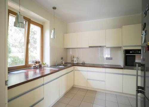 una cocina con armarios blancos y una ventana en Dom z ogrodem blisko centrum en Poznan