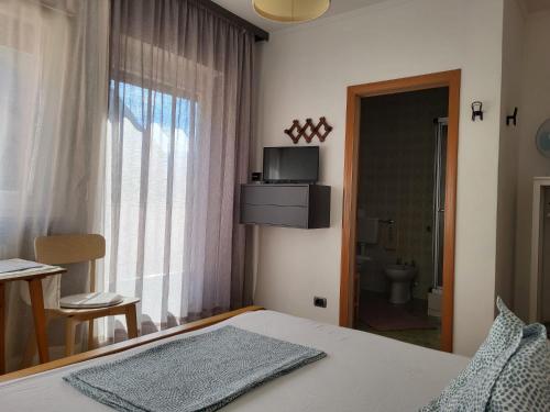 ein Schlafzimmer mit einem Bett und einem Fenster sowie ein Badezimmer in der Unterkunft Albergo Gasthof Salurn in Salurn