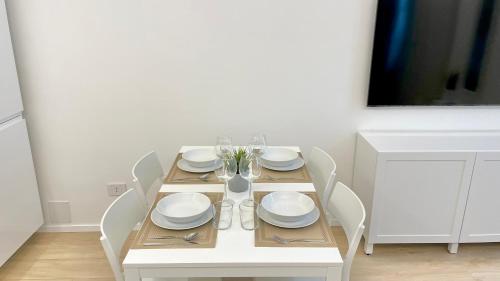 a white dining room table with white plates and silverware at Casa Manzoni Deluxe MXP Town Center in Gallarate