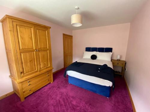 1 dormitorio con 1 cama grande y armario de madera en Derryree House, en Lisnaskea