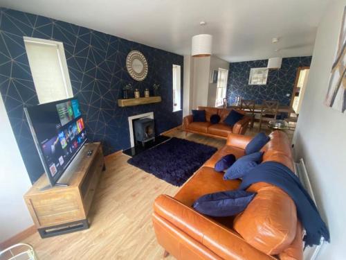 a living room with a leather couch and a tv at Derryree House in Lisnaskea