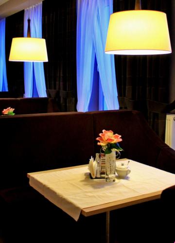a table with two lamps and a table with flowers on it at Hotel Hibiskus in Boguchwała